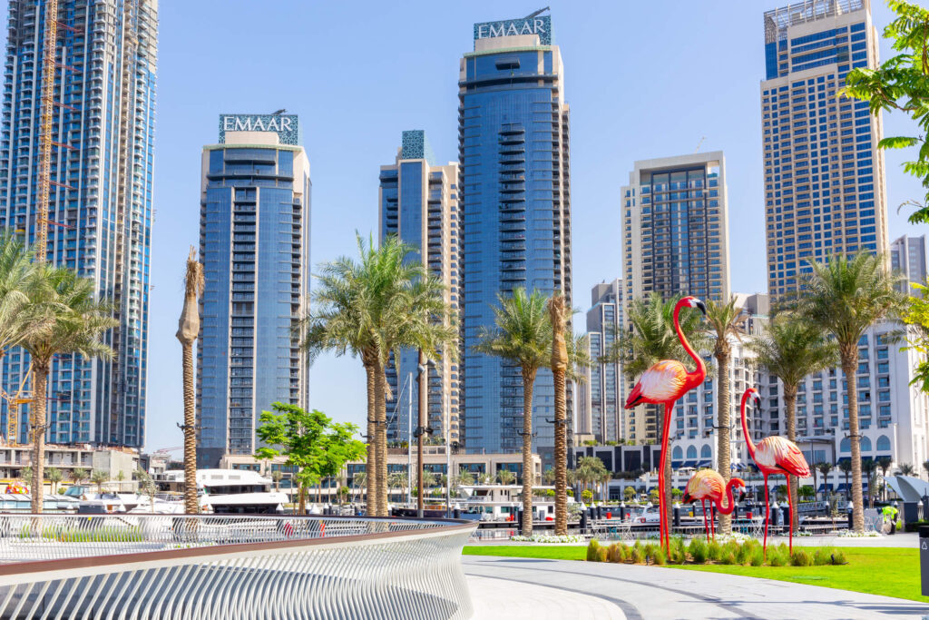 Dubai Creek Harbour promenade and skyline with palm trees and big flamingos sculptures