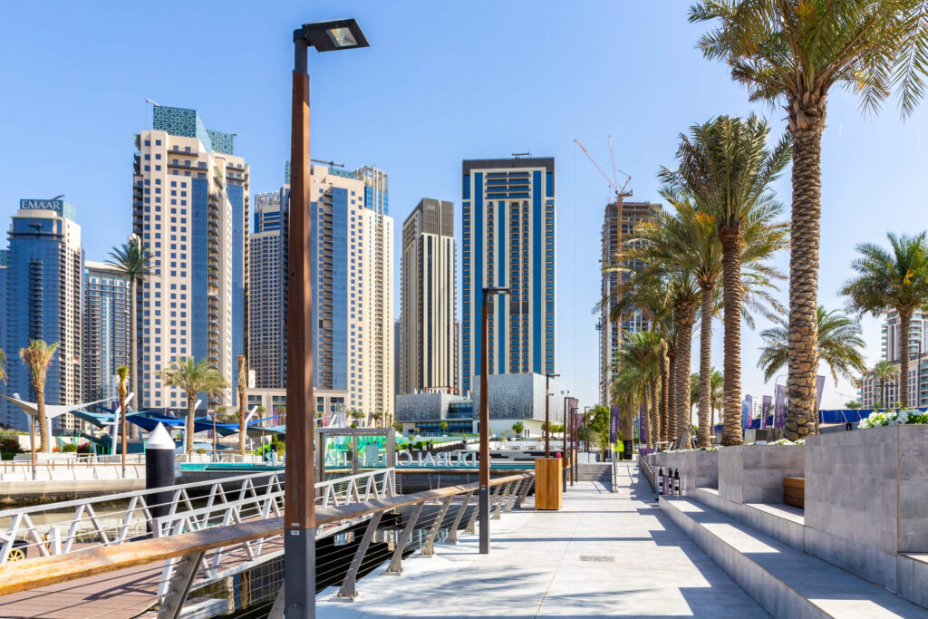 Palm-lined marina promenade at Dubai Creek Harbour with EMAAR residential skyscrapers and waterfront seating, Dubai, UAE