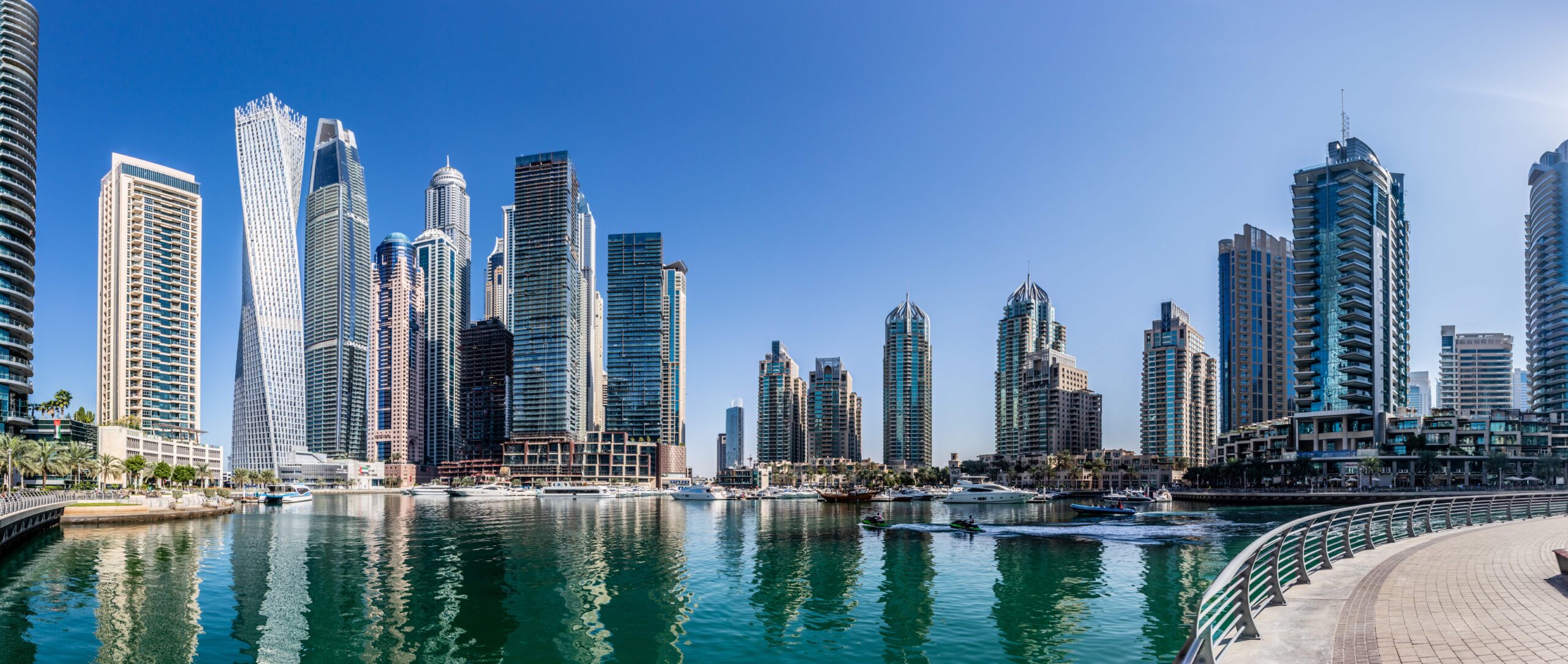 Dubai Marina canal with jet skis and the Cayan Tower twisted high-rise reflecting in the water, Dubai